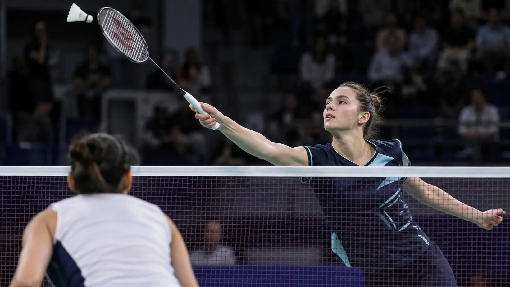 Badminton igračica napada lopticu iznad mreže
